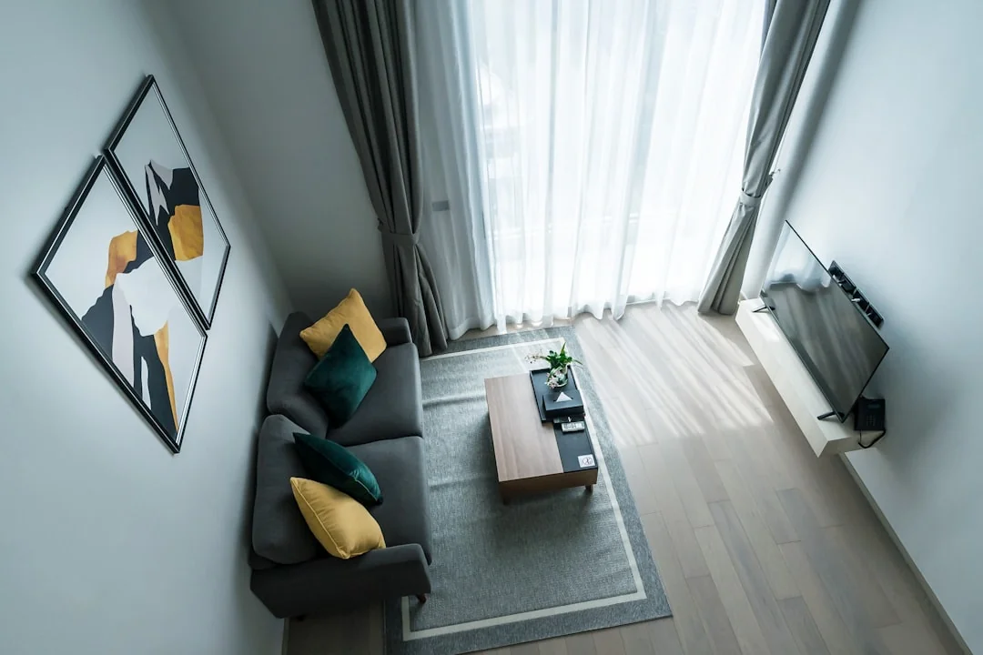 Covered with sheet sofa and floor lamp and packed cardboard boxes in light spacious room of new contemporary house